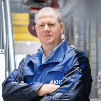 Ein Mann in einer blauen Jacke mit verschränkten Armen