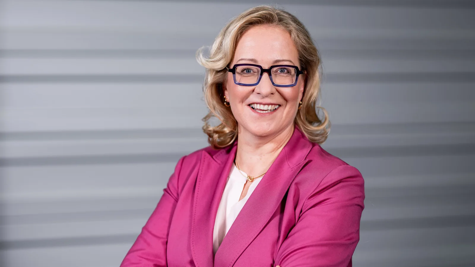 eine Frau mit Brille und rosa Anzug