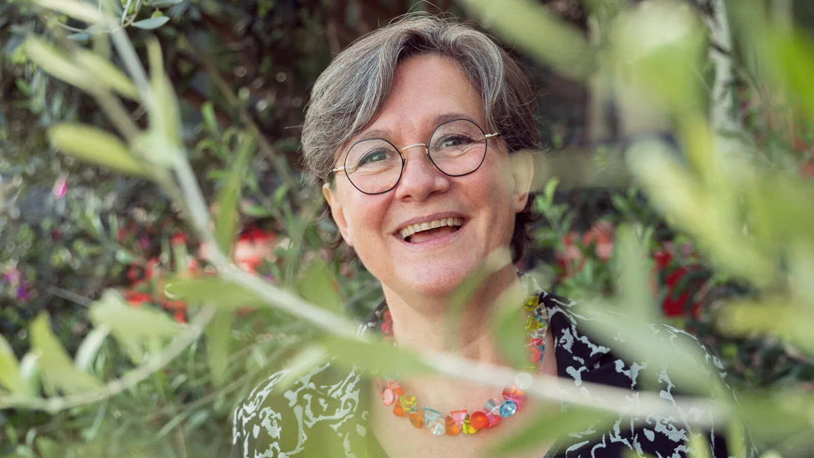 La señora Touchon sonriendo frente a las plantas.