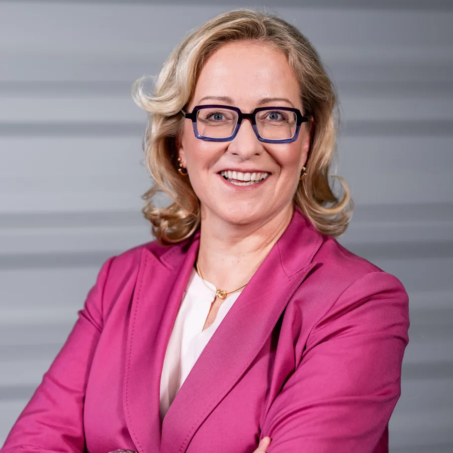 eine Frau mit Brille und rosa Anzug