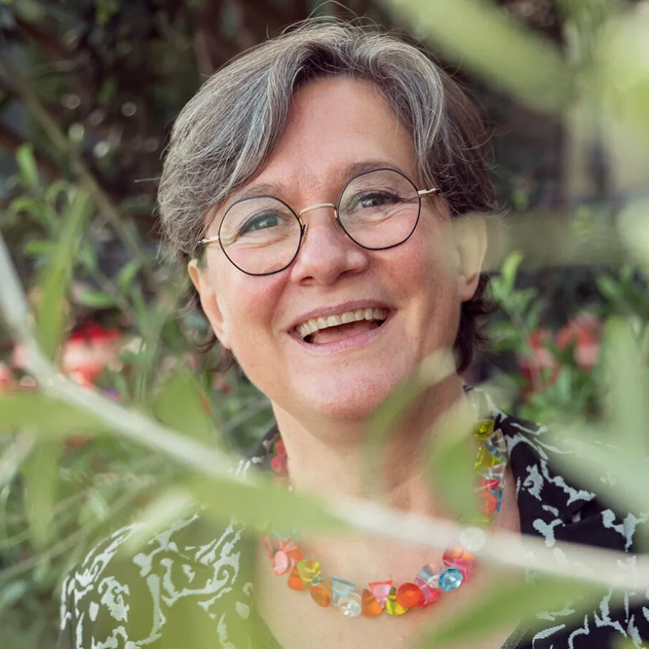 La señora Touchon sonriendo frente a las plantas.